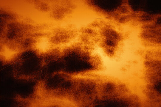 Dramatic orange and black grunge background with fiery cloud patterns and distressed scratch marks suitable for intense graphic design backdrops.