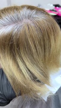 Blonde hair color with visible roots and natural highlights in salon setting