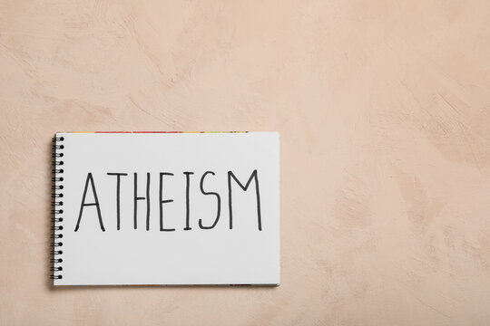 Atheism and secularism concept handwritten word on a spiral notebook page for philosophy religion and belief studies on a textured beige background