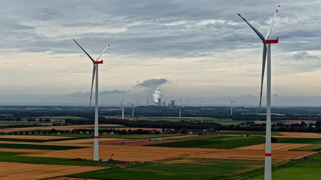 Aerial view of wind turbines in agricultural fields with the Hambach open-pit mine in the background near Elsdorf, Nordrhein-Westfalen, Germany.