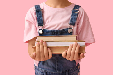 Naklejka premium Little girl with books on pink background