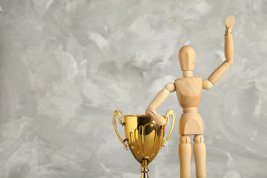 Wooden mannequin with gold cup on grunge background
