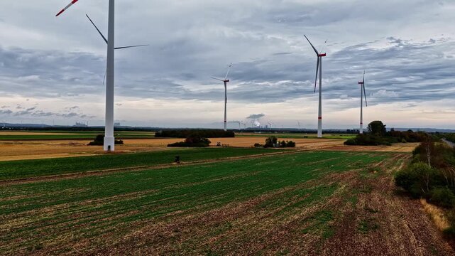 Aerial view of wind turbines in a rural field with the Tagebau Hambach open-pit mine in the background in Elsdorf, Nordrhein-Westfalen, Germany.