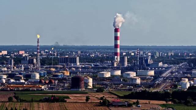Aerial view of the Orlen Plock Production Plant with its distinctive red and white striped chimney, industrial storage tanks, and surrounding infrastructure in Plock, Mazowieckie, Poland.
