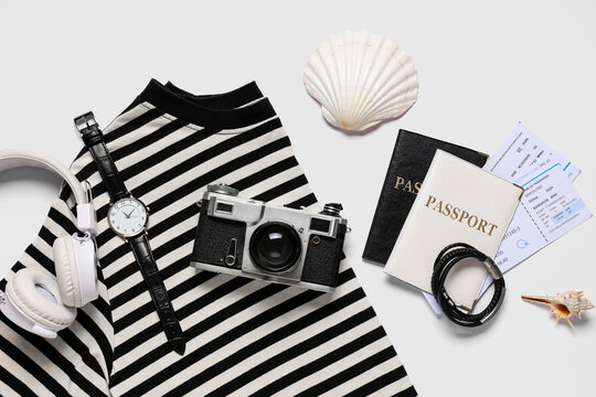 Clothes, photo camera and passports with tickets on white background, closeup