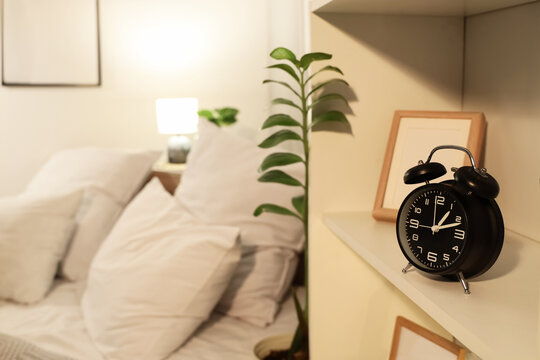Alarm clock on shelf in bedroom at night, closeup