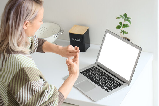 Mature mute woman using sign language during video call at home