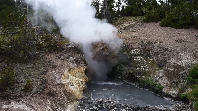 Dragon's Mouth Spring with boiling water and steam rising geothermal feature in Hayden Valley, Yellowstone National Park, summer vacation destination for outdoor nature recreation
