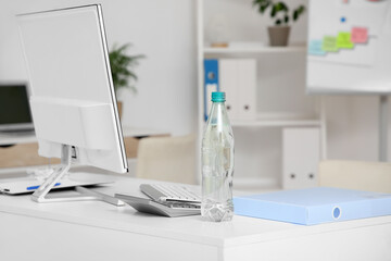 Plastic bottle of water on table in office, closeup