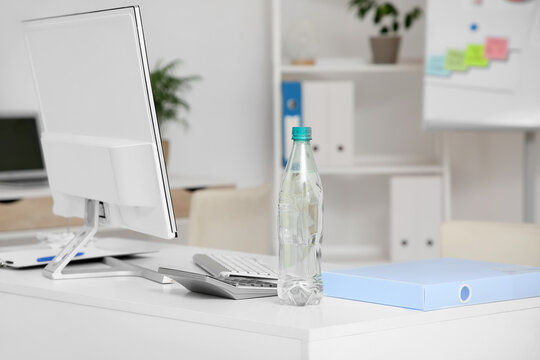Plastic bottle of water on table in office, closeup