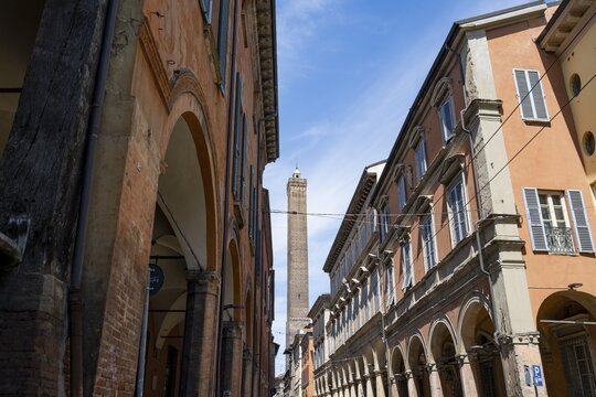 Portici arcades and historic buildings in Strada Maggiore, behind Asinelli Tower of Due Torri, old town, Bologna, Emilia Romagna, Italy