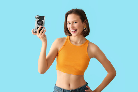 Pretty young woman with photo camera on blue background