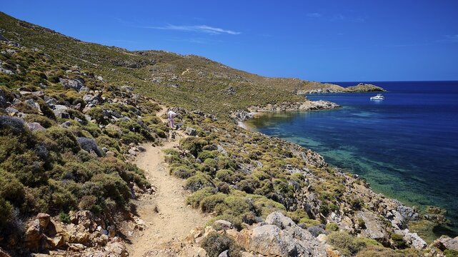 A hiking trail along a rocky coastline with views of the clear sea and blue sky, path to Psili Ammos beach, Patmos, Dodecanese, Greek Islands, Greece