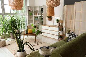 Naklejka premium Interior of living room with houseplants, armchair and shelf unit