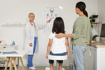 Female pediatrician checking little girls eyesight and mother in clinic © Pixel-Shot