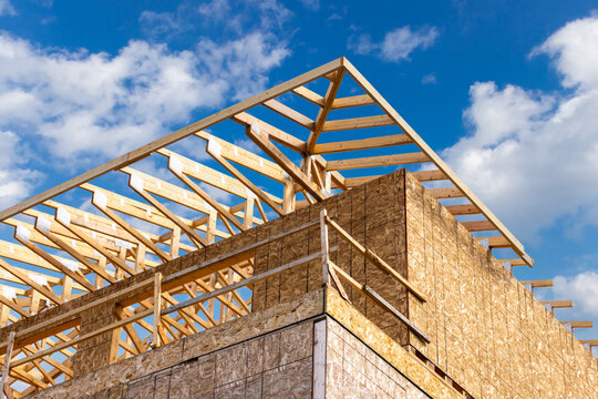 Low rise prefabricated roof trusses held together with metal roof truss connector plates at an industrial construction site with oriented strand chip board sheathed walls