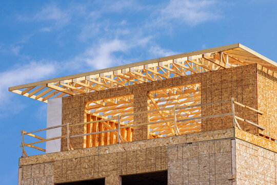 Pre fabricated roof trusses and rafters held together with metal roof truss connector plates at an residential construction site with oriented strand chip board sheathed walls