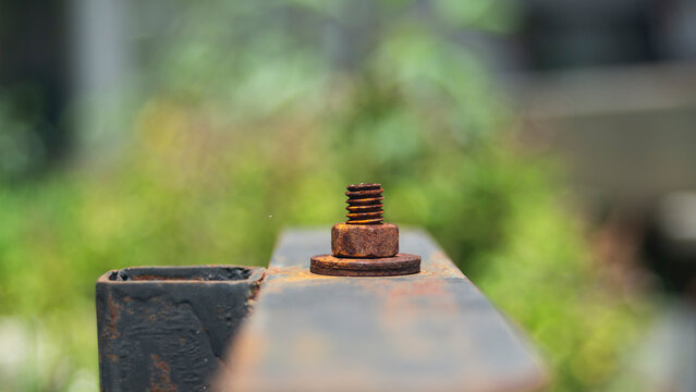 Close up of a heavily rusted metal bolt, nut, and washer on an outdoor iron structure.A high-quality close-up macro shot focusing on a single, heavily corroded metal bolt fastened with a rusty 