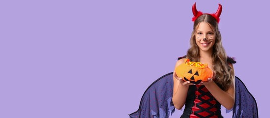 Naklejka premium Halloween celebration and trick or treat, happy girl in devil costume holding pumpkin candy bucket on purple background with copy space for seasonal event