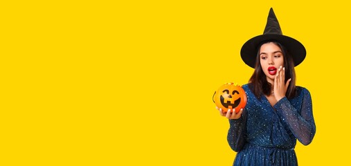 Naklejka premium Halloween celebration and party fun, surprised young woman in witch hat holding pumpkin candy bucket with sweets on a bright yellow background