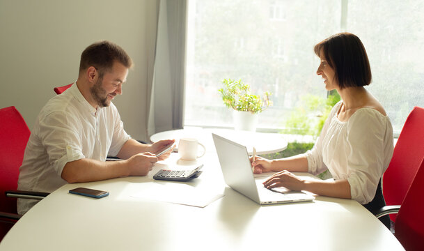 two professional people employees working together in the office discussing developing strategy calculating budget planning consulting calculating expenses using electronic devices