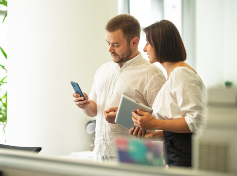 two professional people employees working together in the office discussing developing strategy calculating budget planning consulting calculating expenses using electronic devices