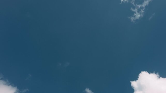 Large expanse of blue sky in the center with small clouds around the edges