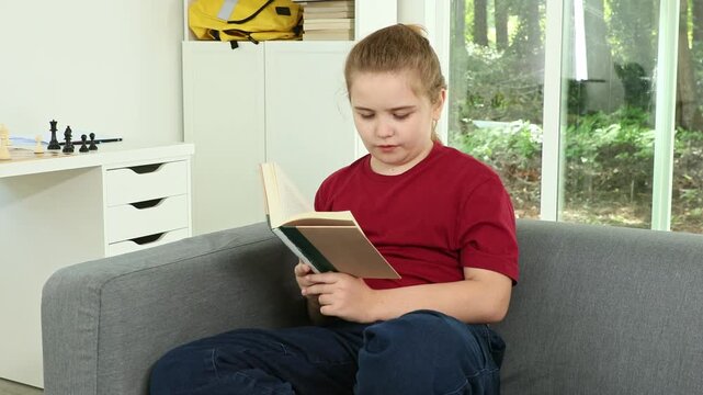 Cute child reading a book at home. Smart kid studying with textbook. Schoolboy reading a book homework in cozy room. Student child focused on reading book. Clever boy reading story at classroom.