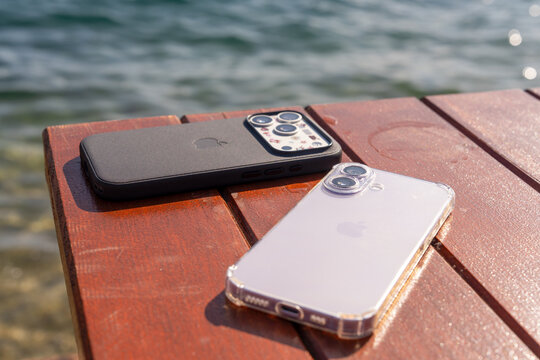 Bar, Montenegro: February 6, 2026:  A  two new Apple iPhone 17 Pro smartphones on a sunlit wooden pier beside calm water, a concept of mobile device protection outdoors.