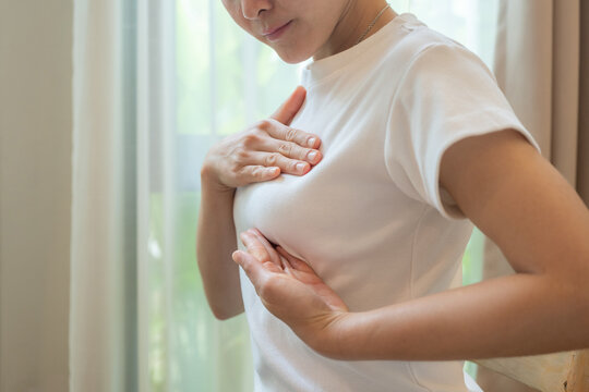 Cropped shot view of young Asian woman touching her breast for checking breast size or cancer awareness.