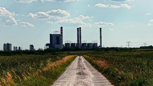 Aerial view of Patnow Power Plant with tall chimneys and industrial structures surrounded by fields and power lines in Konin, Wielkopolskie, Poland.