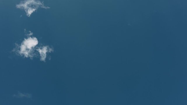 Large expanse of blue sky in the center with small clouds around the edges