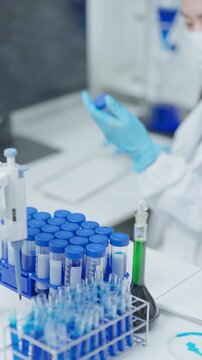 Laboratory technician reviewing a sample while typing on a computer in a clean clinical workspace for data analysis and documentation.