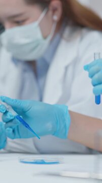 Close-up of a laboratory technician using a pipette to drop liquid sample into a petri dish during scientific testing in a clean clinical lab.