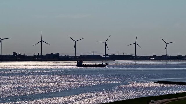 Aerial view of wind turbines and a cargo ship on the water near the industrial area of Emden, Niedersachsen, Germany.