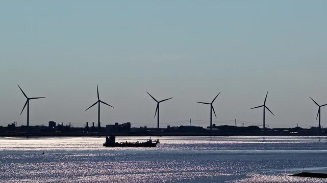 Aerial view of wind turbines along the Ems river with industrial infrastructure in the background in Emden, Niedersachsen, Germany.
