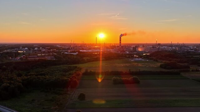 Aerial view of the Orlen Production Plant at sunset with industrial chimneys and smoke plumes rising over the landscape in Plock, Mazowieckie, Poland.
