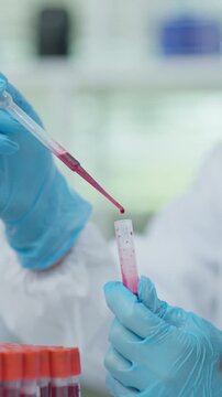 Close-up of a laboratory technician holding a blood sample test tube during medical testing and laboratory analysis in a clean clinical environment.