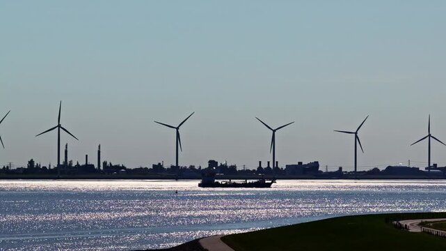 Aerial view of wind turbines and a cargo ship near the Volkswagenwerk Emden industrial facility along the coastline in Emden, Niedersachsen, Germany.