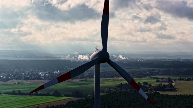 Aerial view of a wind turbine with the PCK Raffinerie GmbH refinery in the distance over the landscape of SchwedtOder, Brandenburg, Germany.