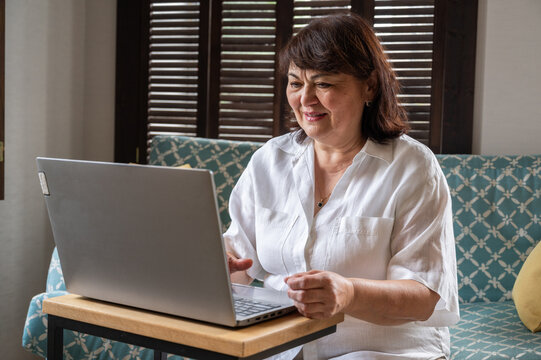 Happy senior female works on a laptop from home. Remore education, work, technologies concept