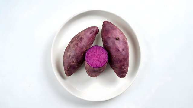 Purple sweet potatoes on white plate with cut open tuber