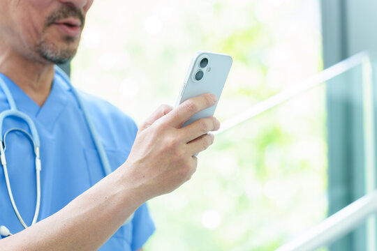 スマートフォンを使う中高年の医師の手元