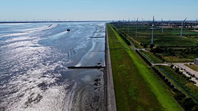 Aerial view of Volkswagenwerk Emden factory near the Ems river with wind turbines and a ship in the water in Emden, Niedersachsen, Germany.