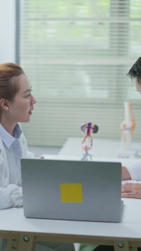 Doctor discussing male urinary system and kidney health during consultation with laptop in clinic, suitable for telehealth and remote healthcare concepts.