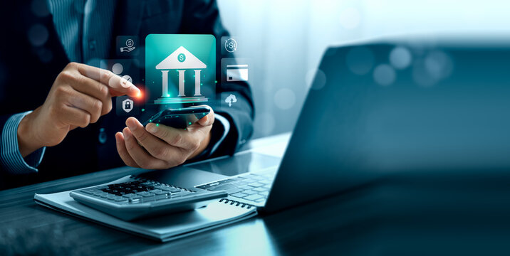 Mobile banking concept with business professional using smartphone beside laptop and calculator showing virtual bank interface digital payment security and online financial service