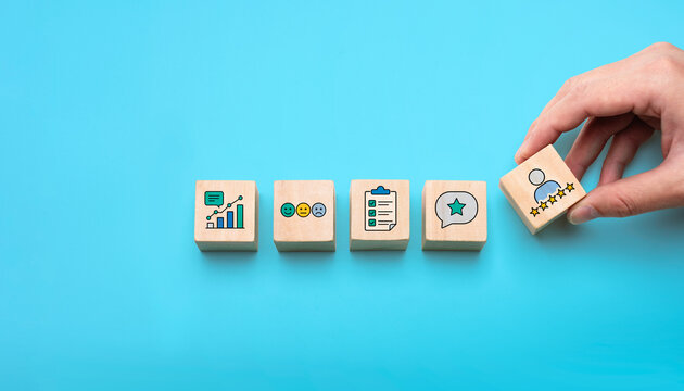 Customer satisfaction feedback concept with wooden blocks showing review rating, survey checklist, emotion icons, comment bubble, service quality and customer experience analytics