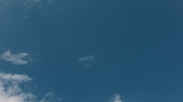 Large expanse of blue sky in the center with small clouds around the edges