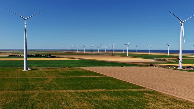 Aerial view of wind turbines at the Eemshaven Industrial Energy Complex in a vast agricultural landscape near the Wadden Sea in Eemshaven, Groningen, Netherlands.