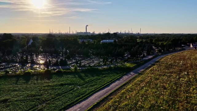 Aerial view of Orlen Plock Production Plant at sunset, with a cemetery and fields in the foreground in Plock, Mazowieckie, Poland.